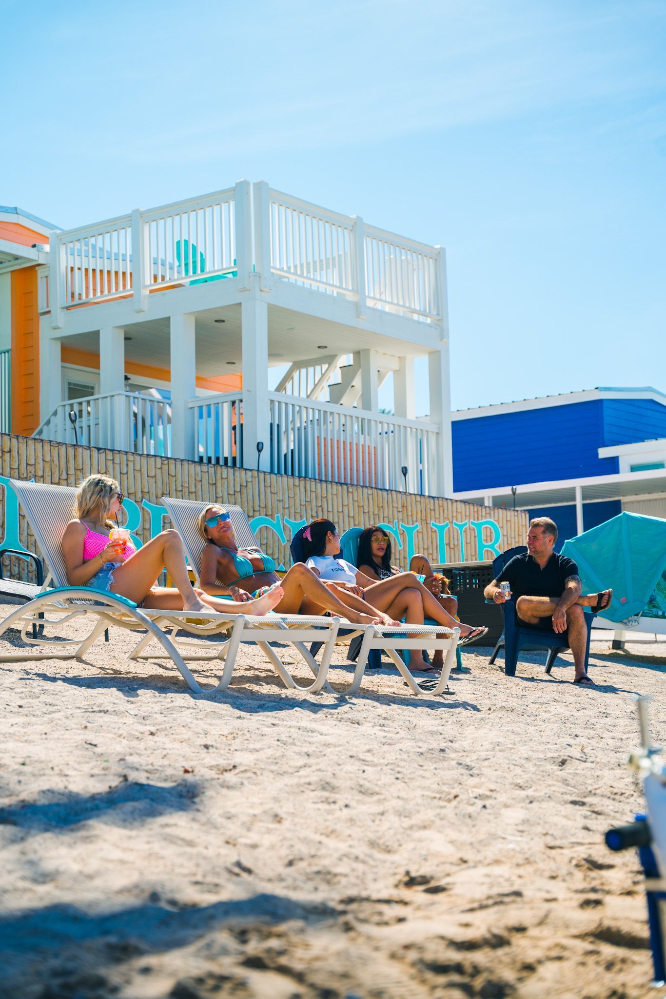 A group of people are sitting in lounge chairs on the beach.