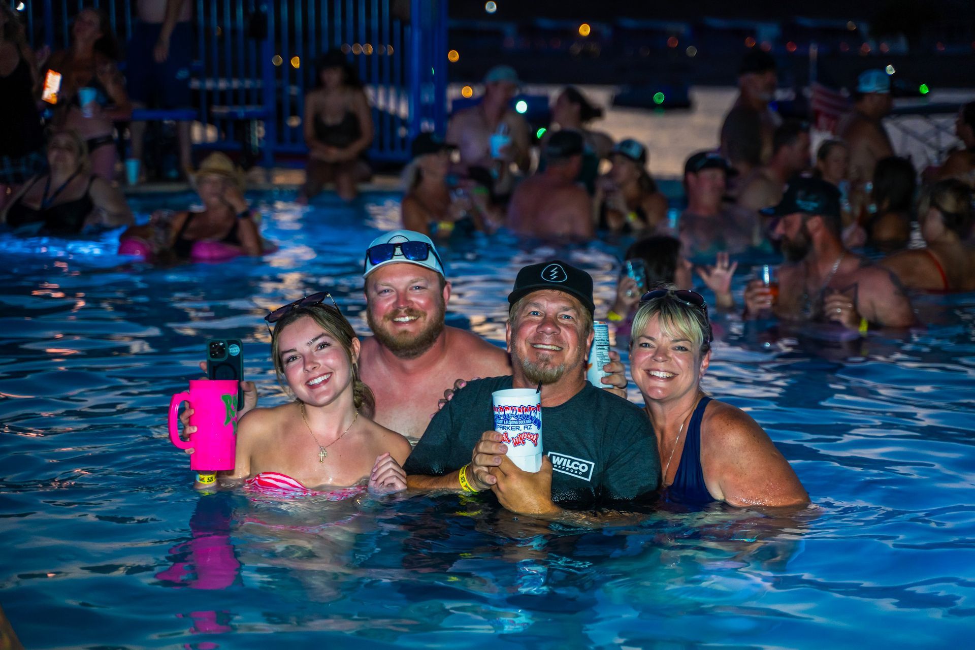 A group of people are standing in a swimming pool holding drinks.