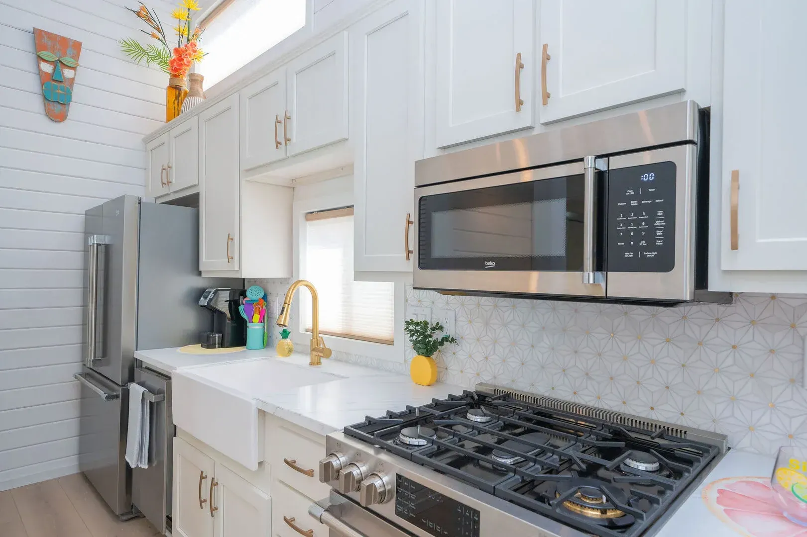 A kitchen with a stove , microwave , refrigerator and sink.