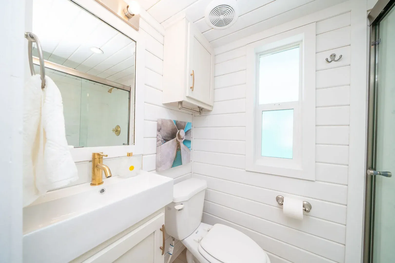 A bathroom with a toilet , sink , mirror and shower.