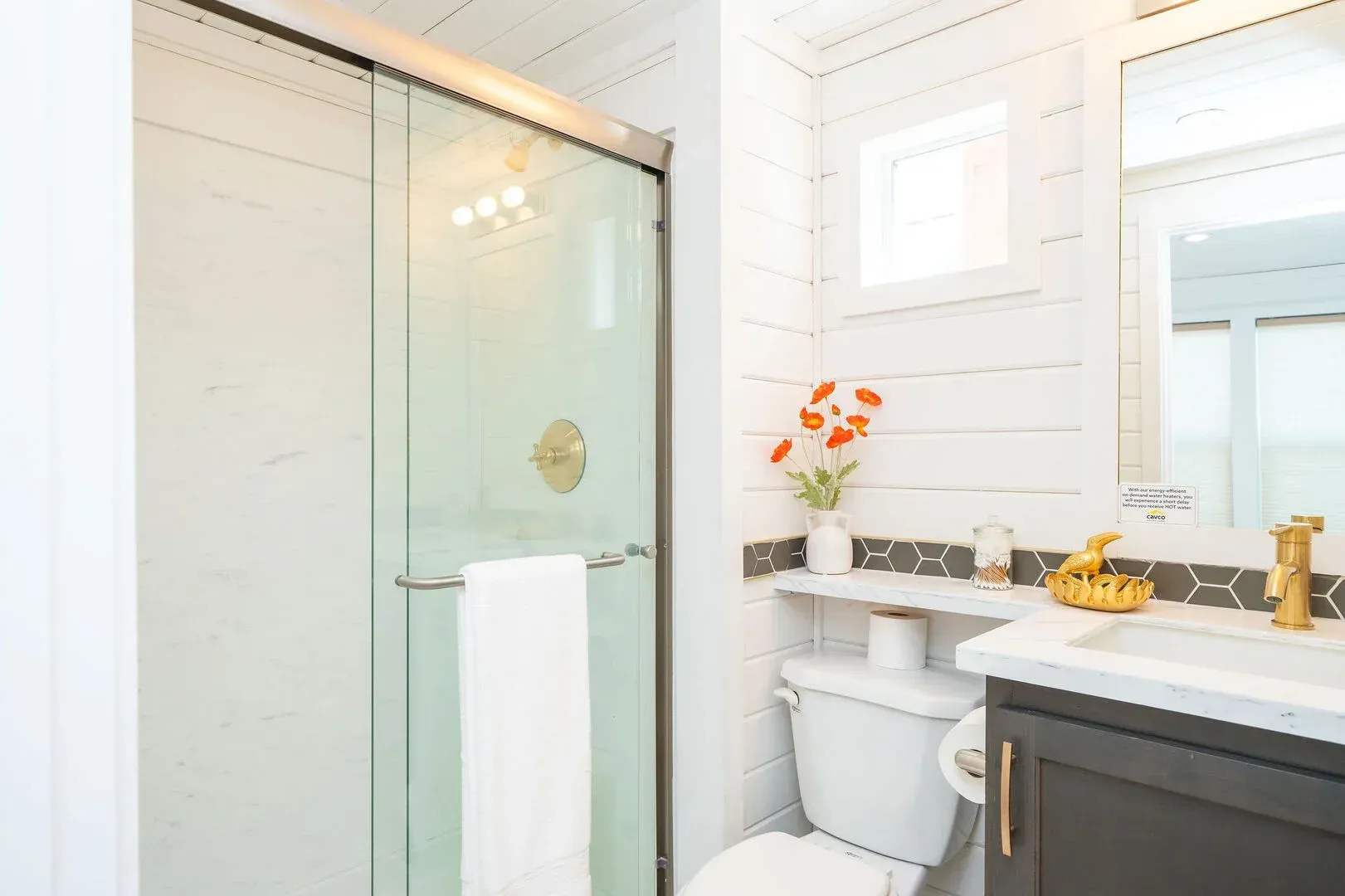 A bathroom with a toilet , sink , mirror and shower stall.