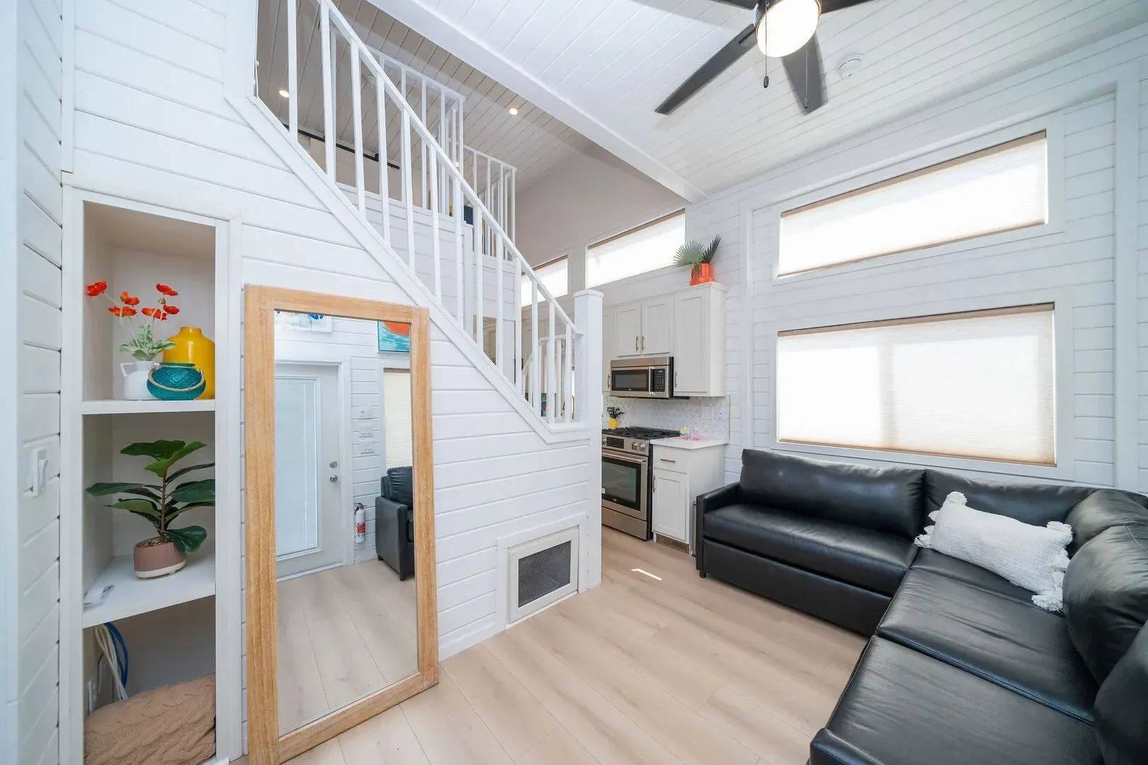 A living room with a couch , mirror and stairs leading up to the second floor.
