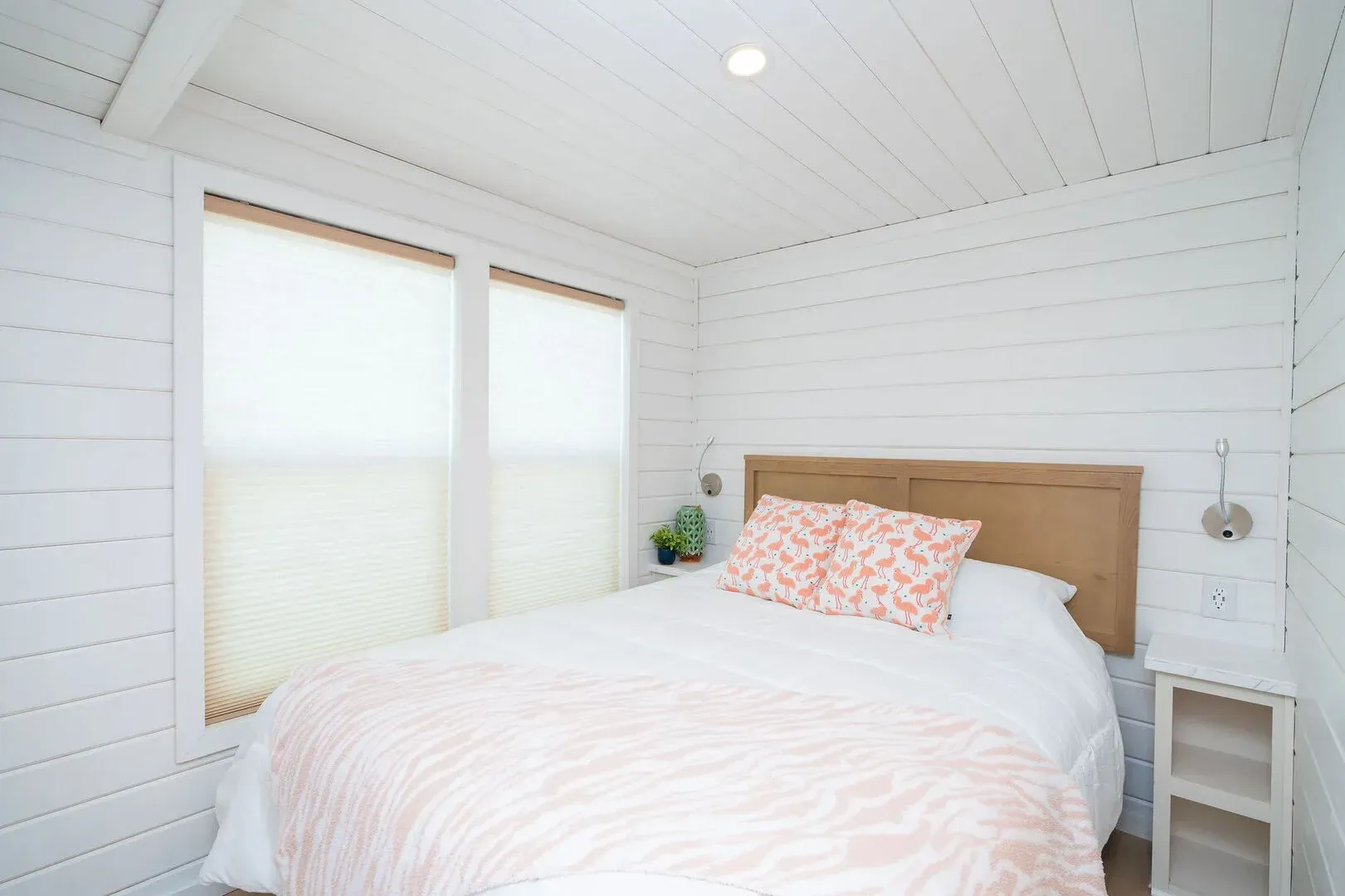 A bedroom with a bed , nightstand , and two windows.