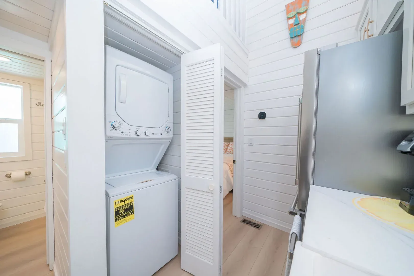 A washer and dryer are in a closet in a kitchen.