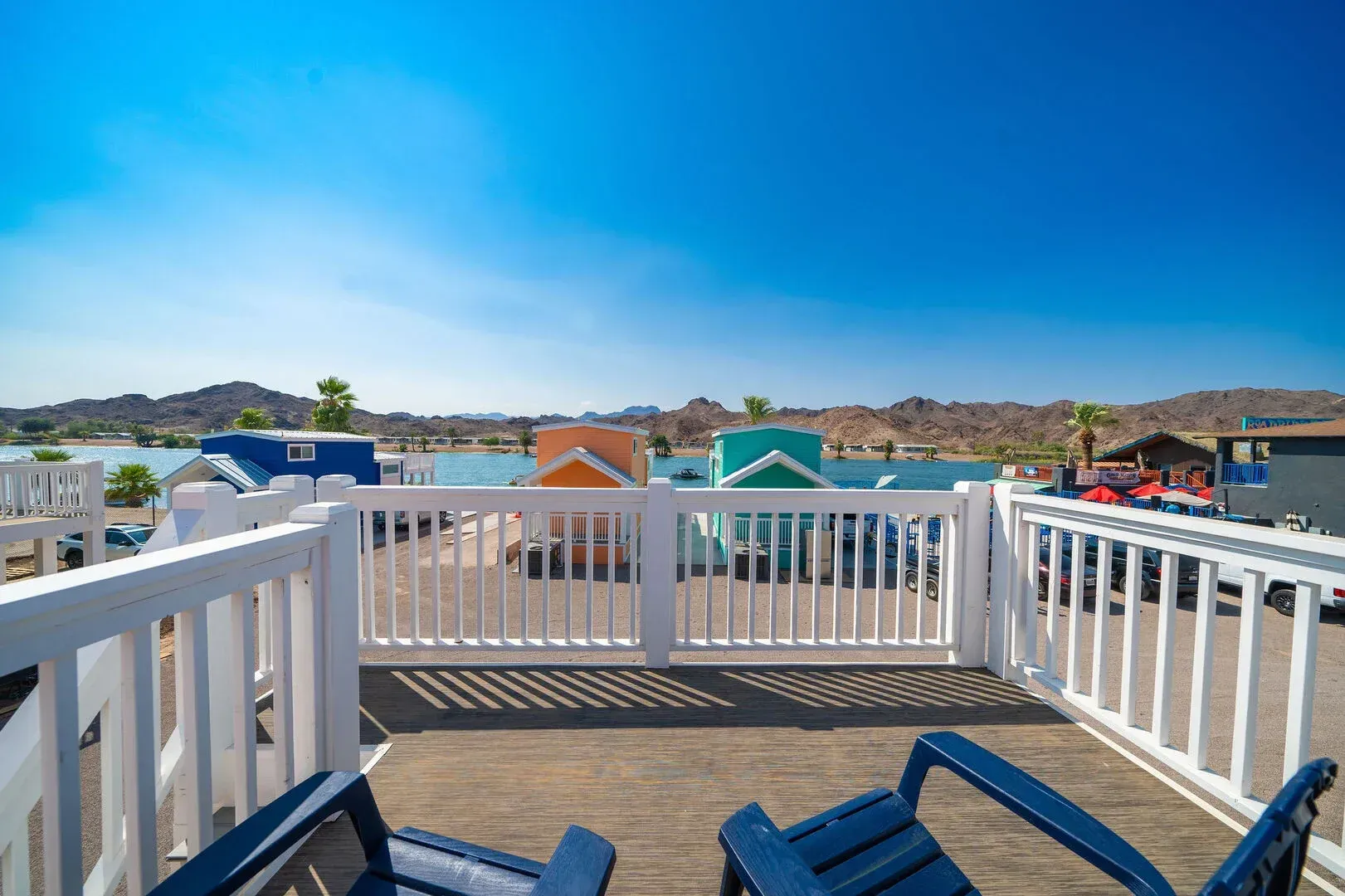 A balcony with two chairs and a white railing overlooking a lake.