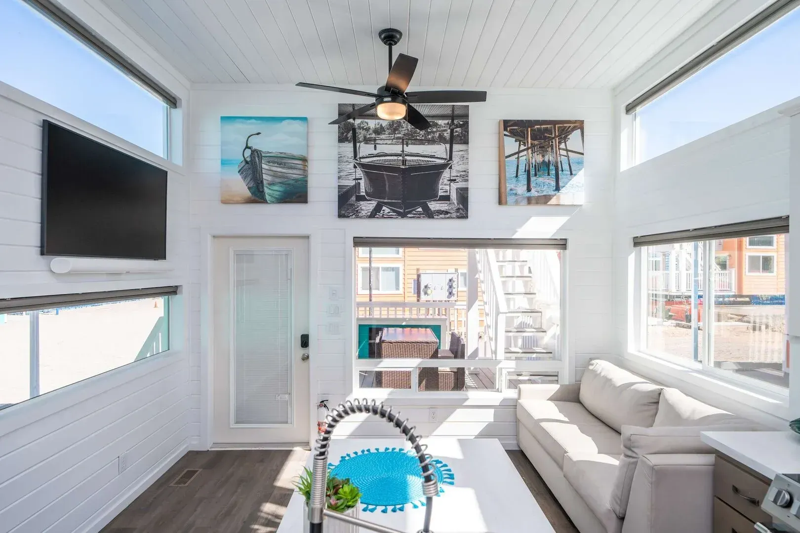 A living room with a couch , television , and ceiling fan.