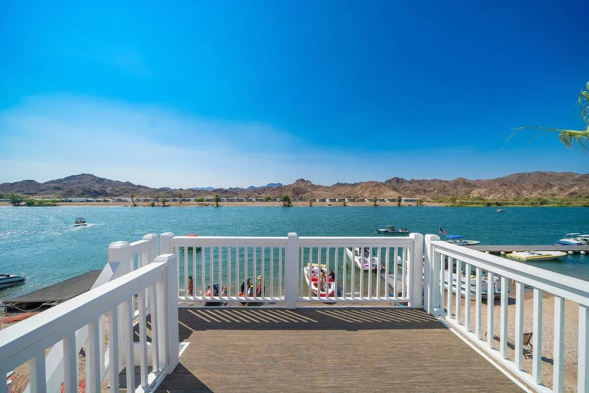 A view of a lake from a deck with a white railing.