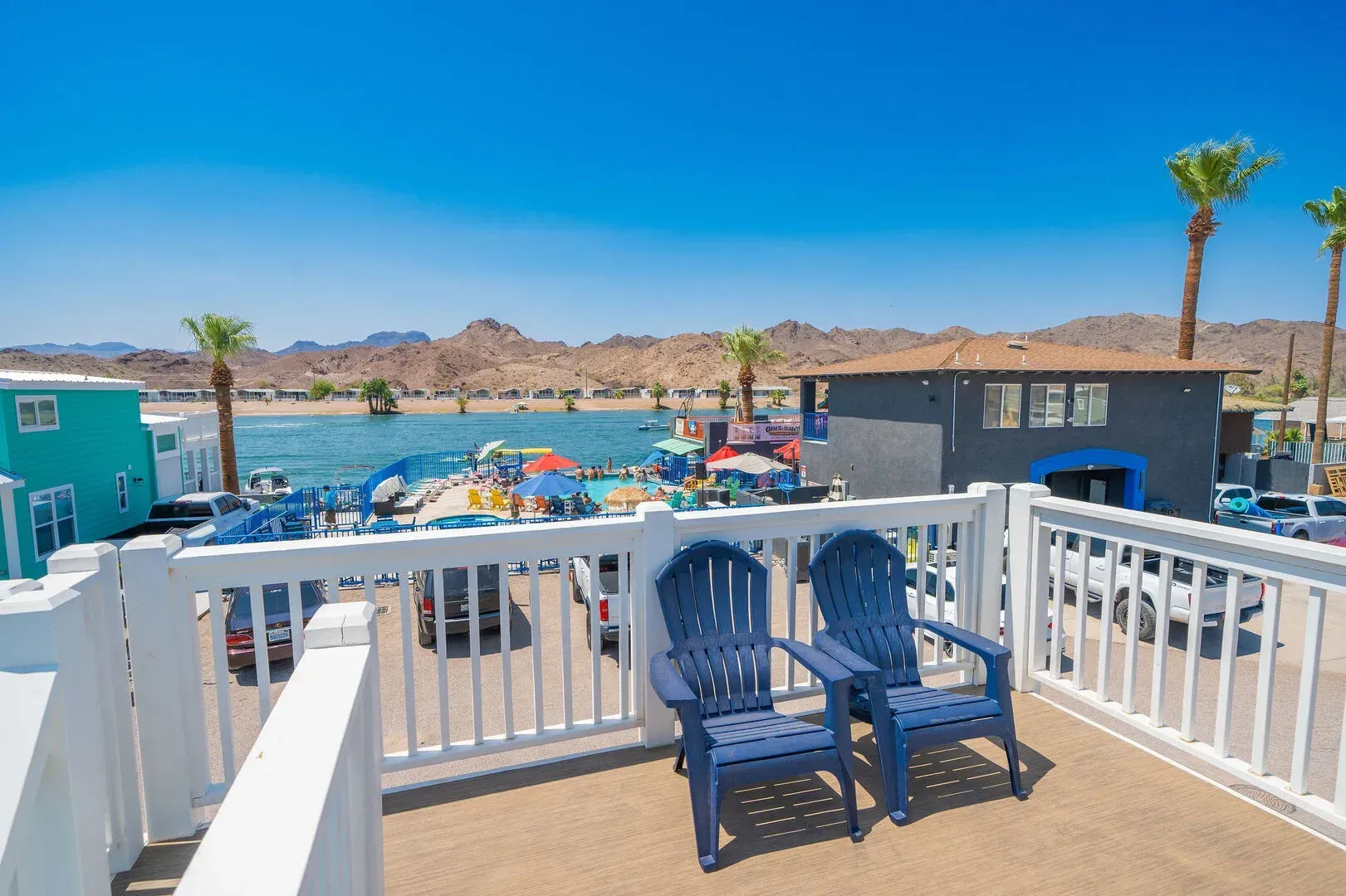 Two blue chairs are sitting on a balcony overlooking a body of water.