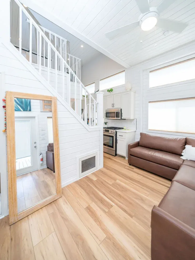 A living room with a couch , mirror and stairs.