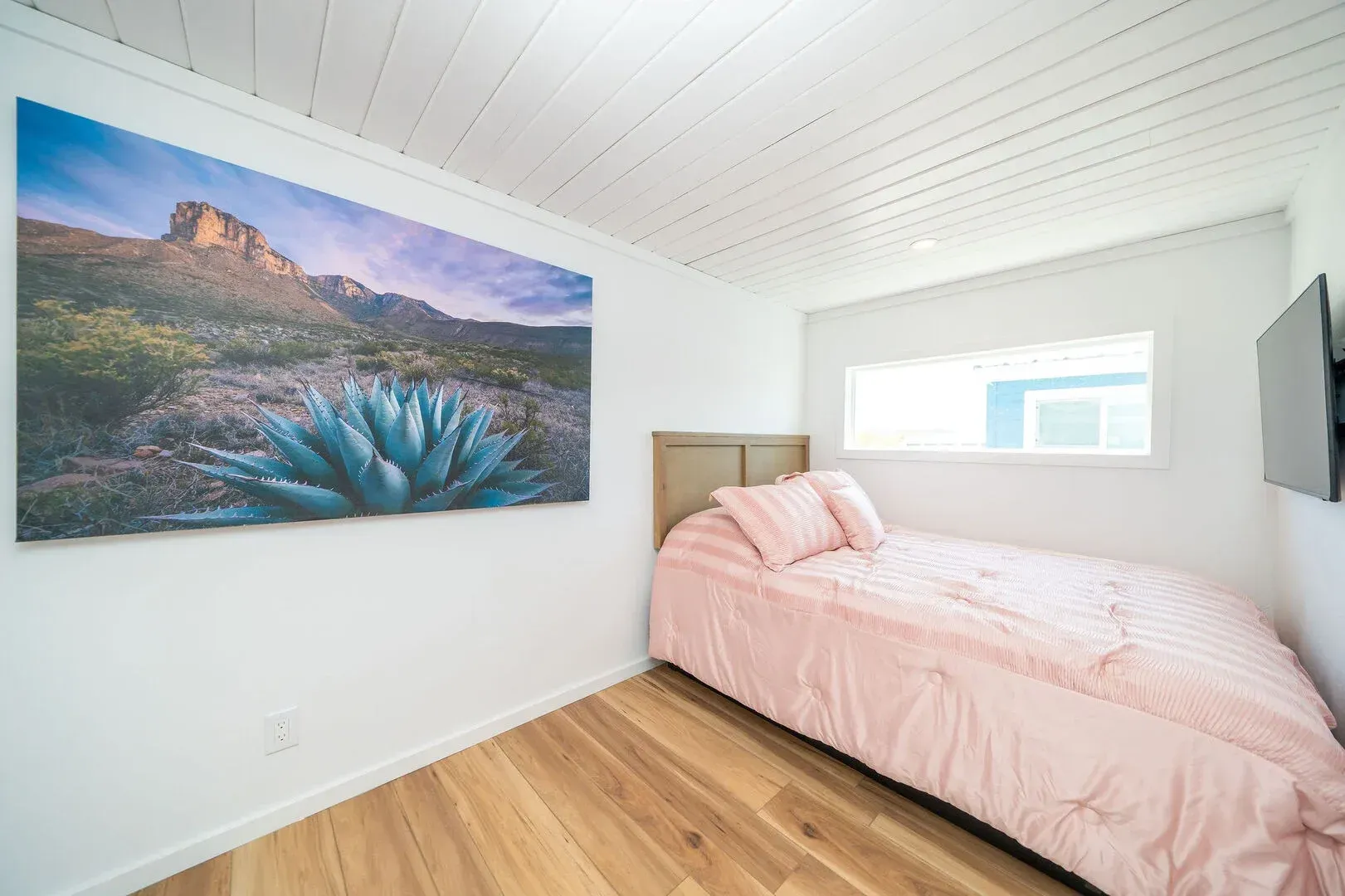 A bedroom with a single bed and a large painting on the wall.