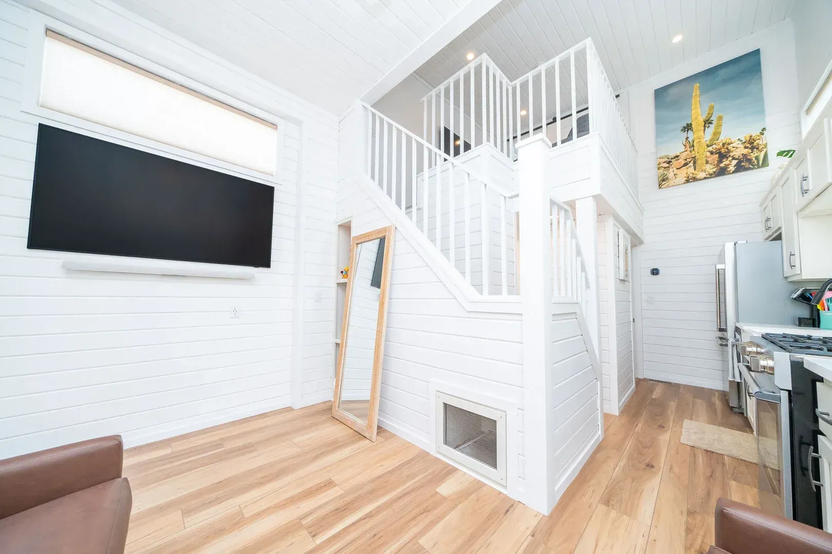 A living room with hardwood floors and a staircase leading to the second floor.