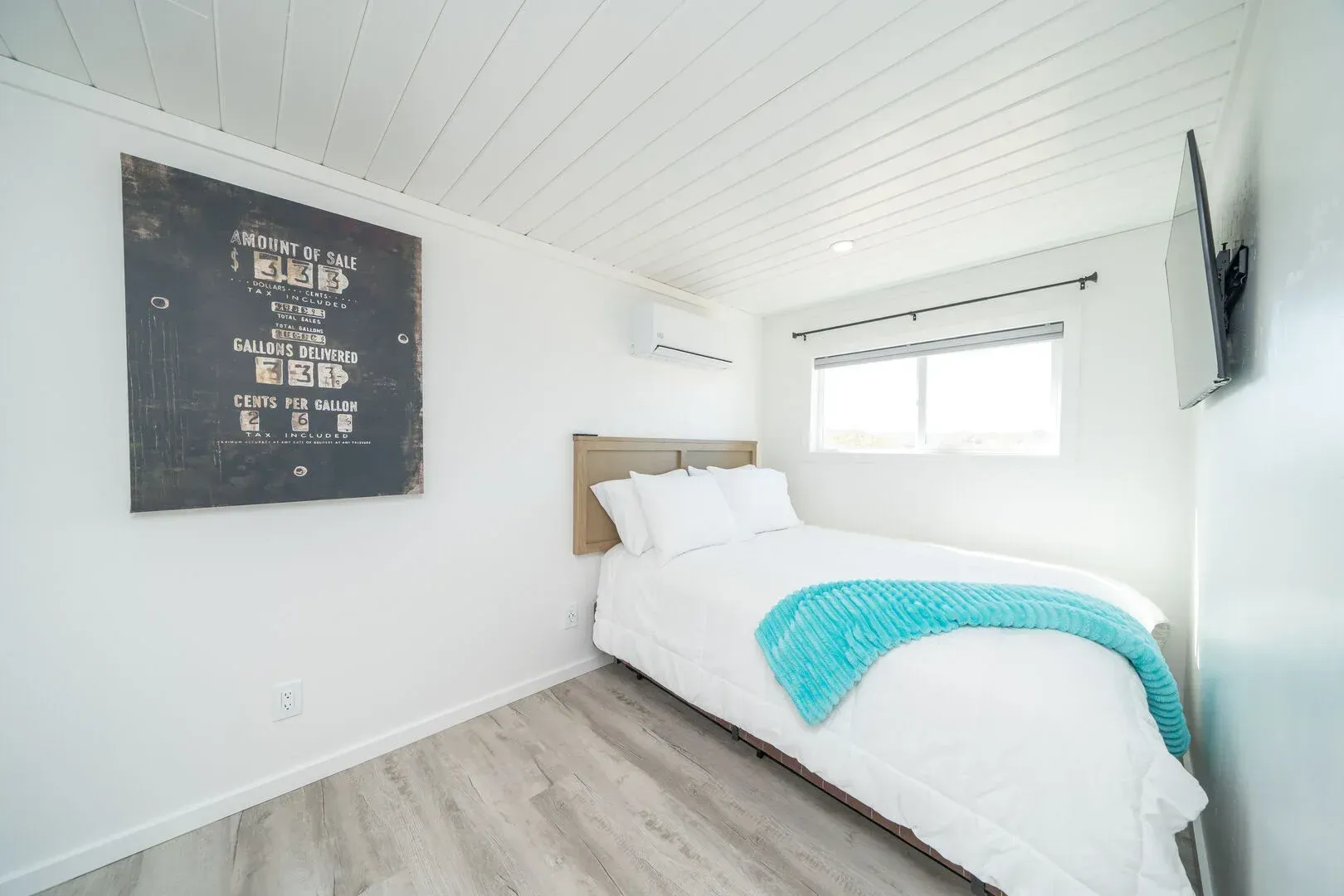 A bedroom with a bed , television and a painting on the wall.