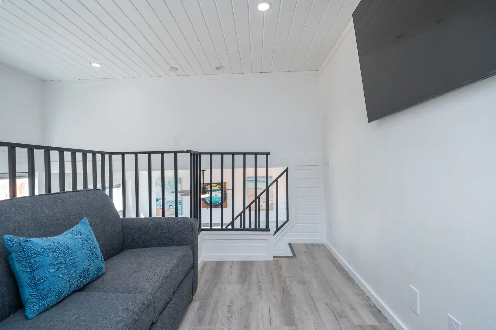 A living room with a couch and a television on the wall.