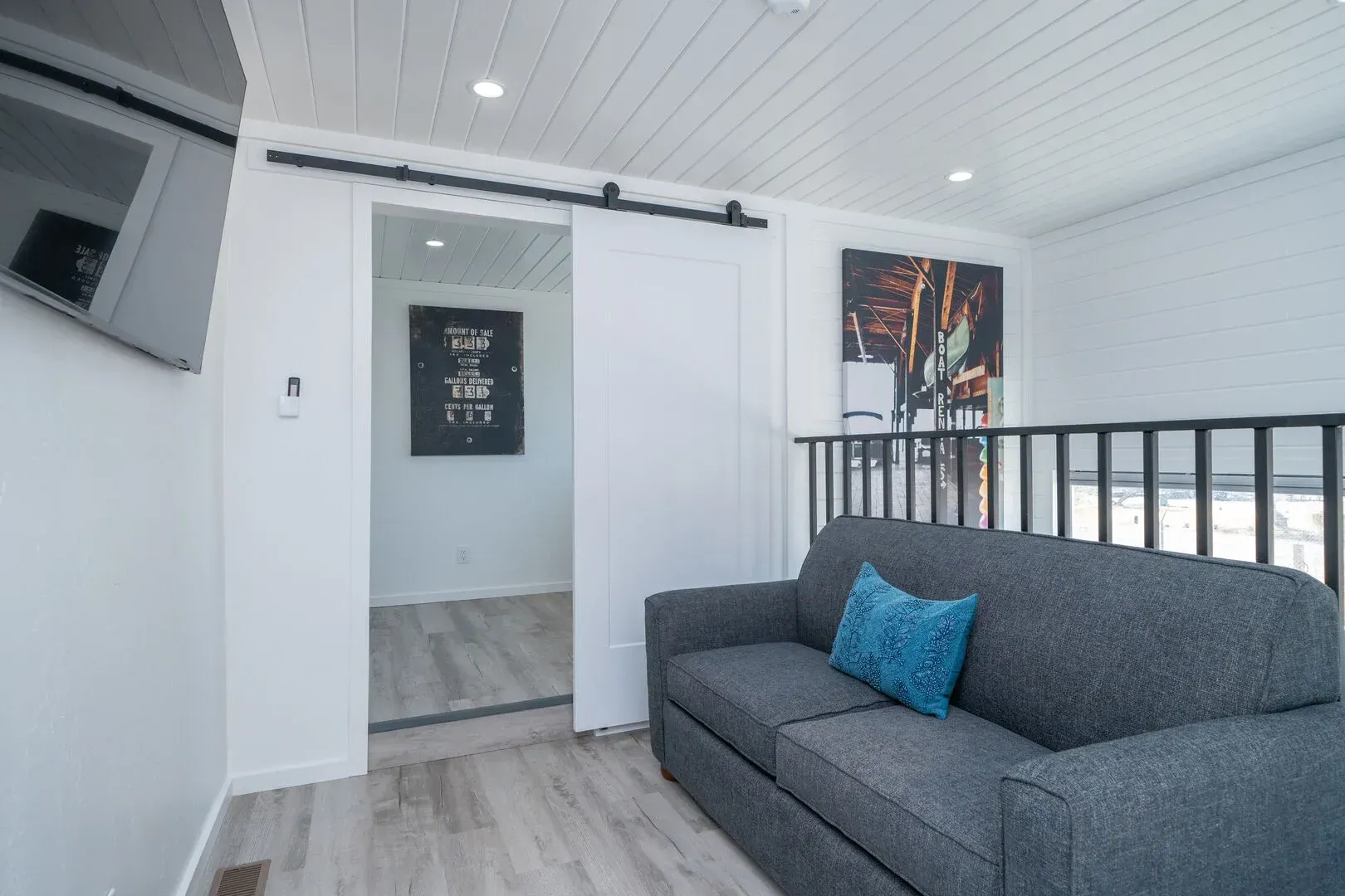 A living room with a couch , television , and sliding barn door.