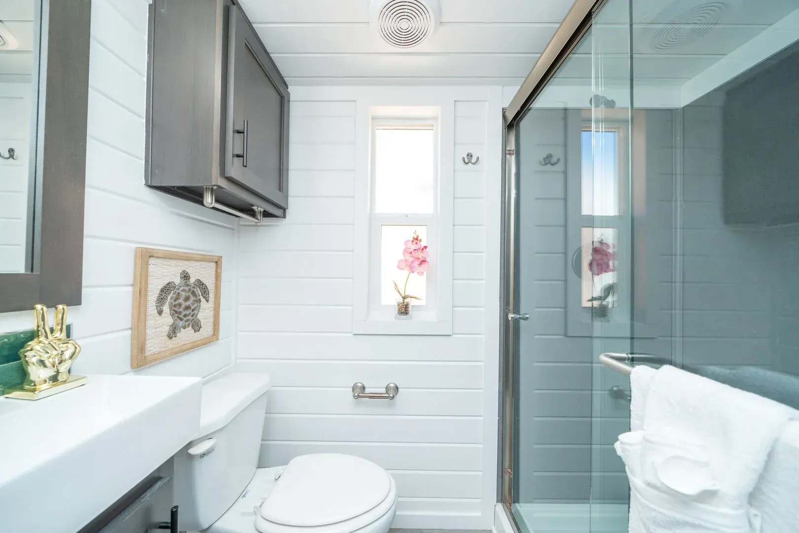 A bathroom with a toilet , sink , mirror and shower.