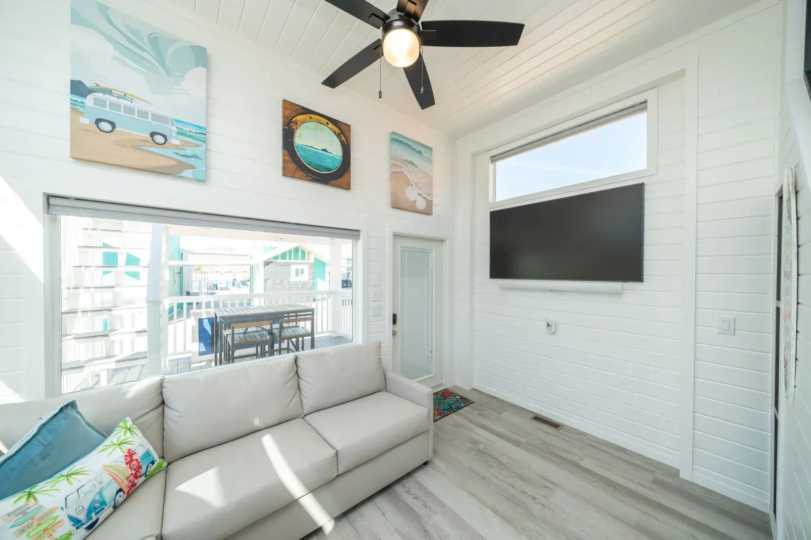 A living room with a couch , television , and ceiling fan.