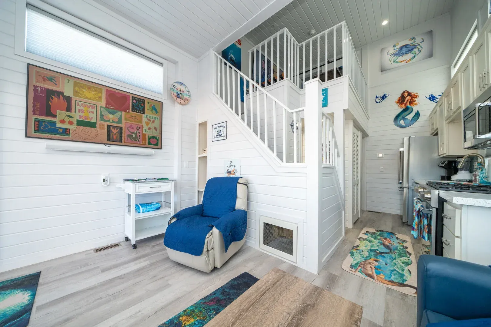A living room with a blue chair and stairs leading up to the second floor.