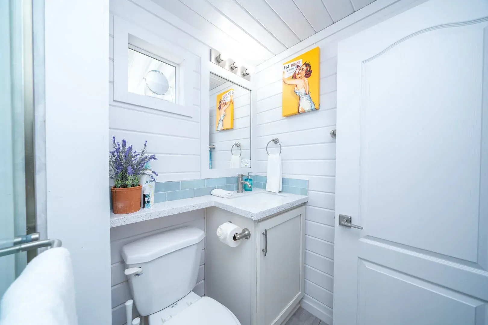 A bathroom with a toilet , sink and mirror.