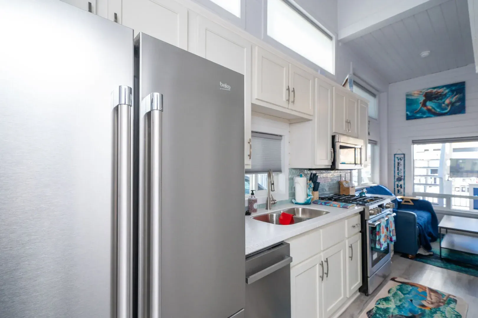 A kitchen with a stainless steel refrigerator and white cabinets.