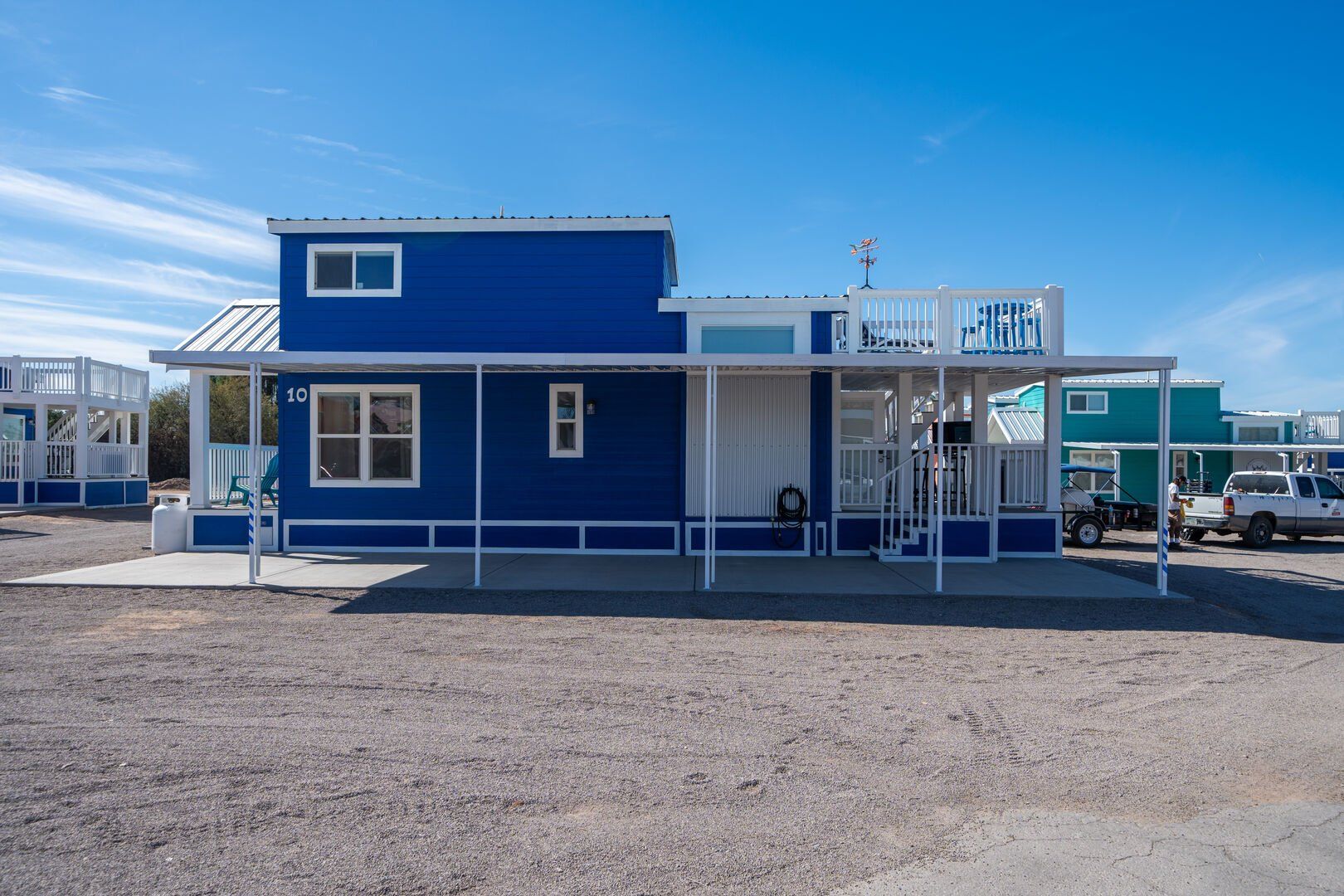 A blue and white house with a porch and a blue sky in the background.