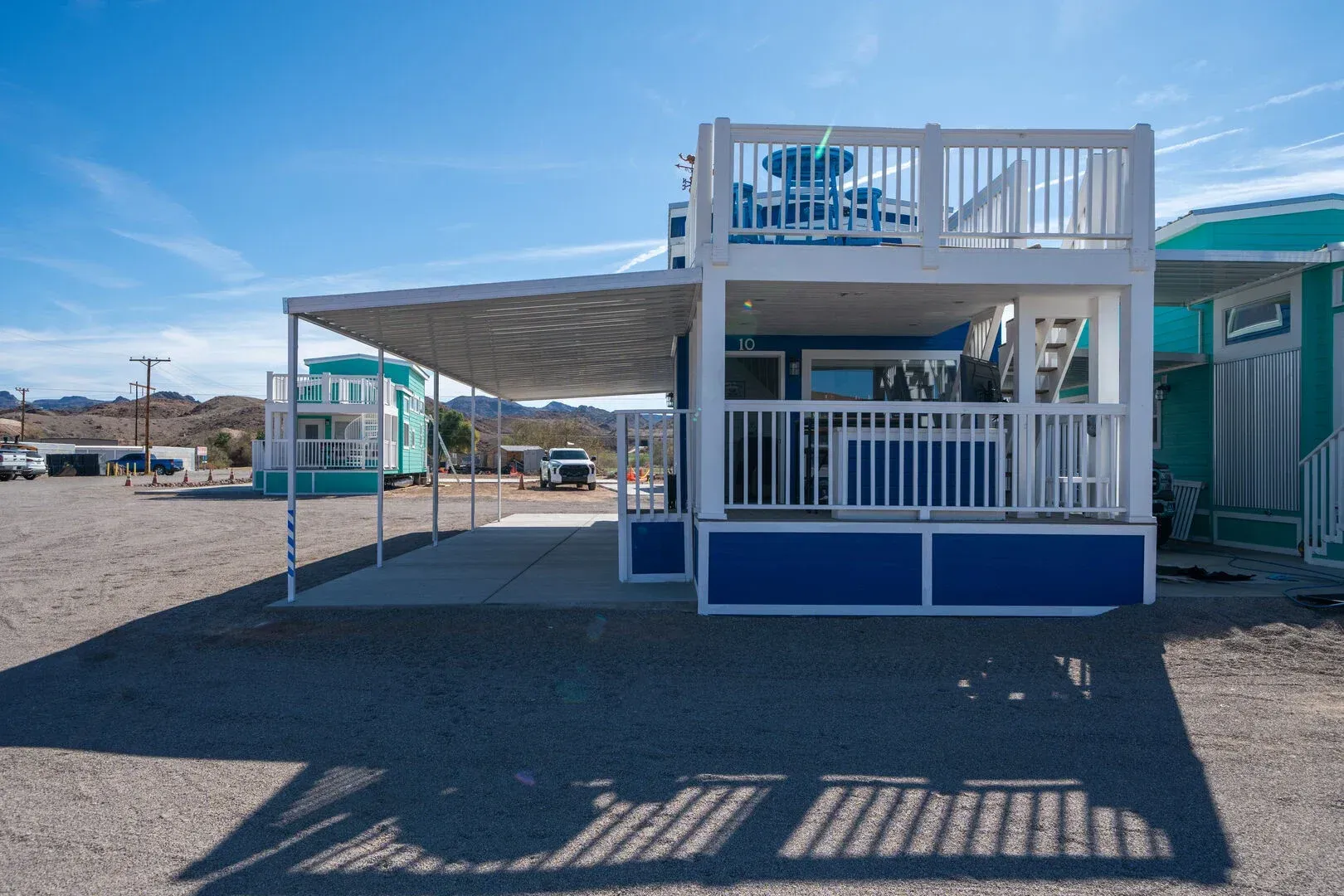 A blue and white mobile home with a balcony on top of it.