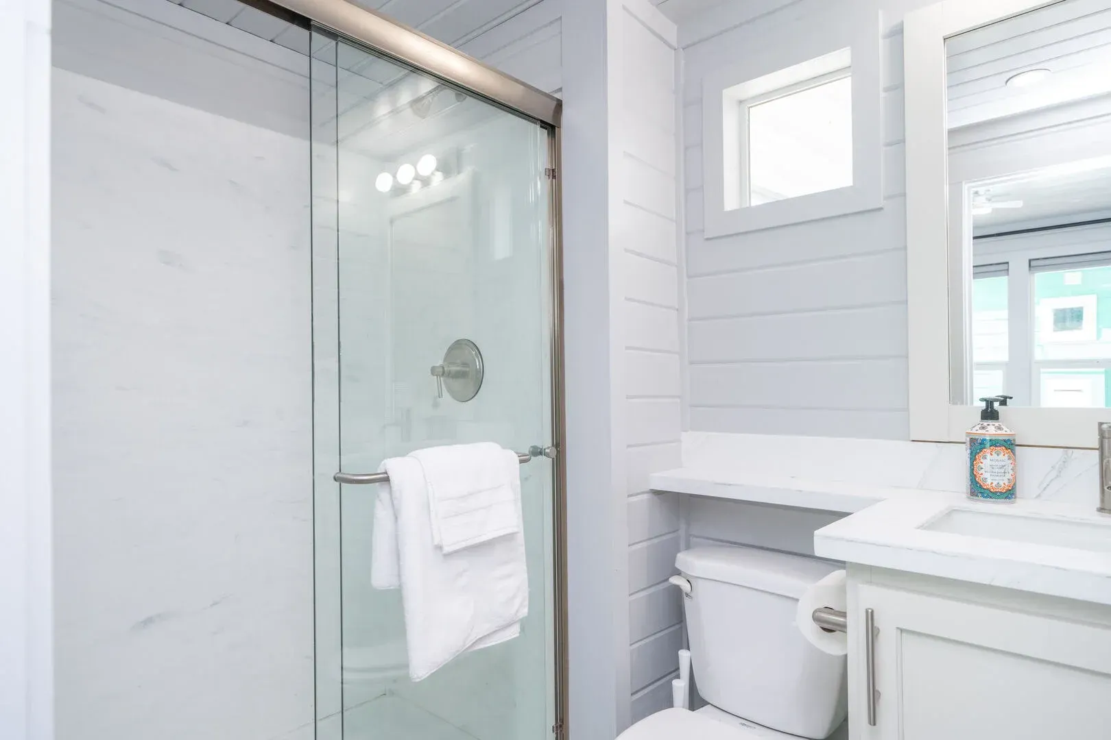 A bathroom with a toilet , sink , mirror and shower.