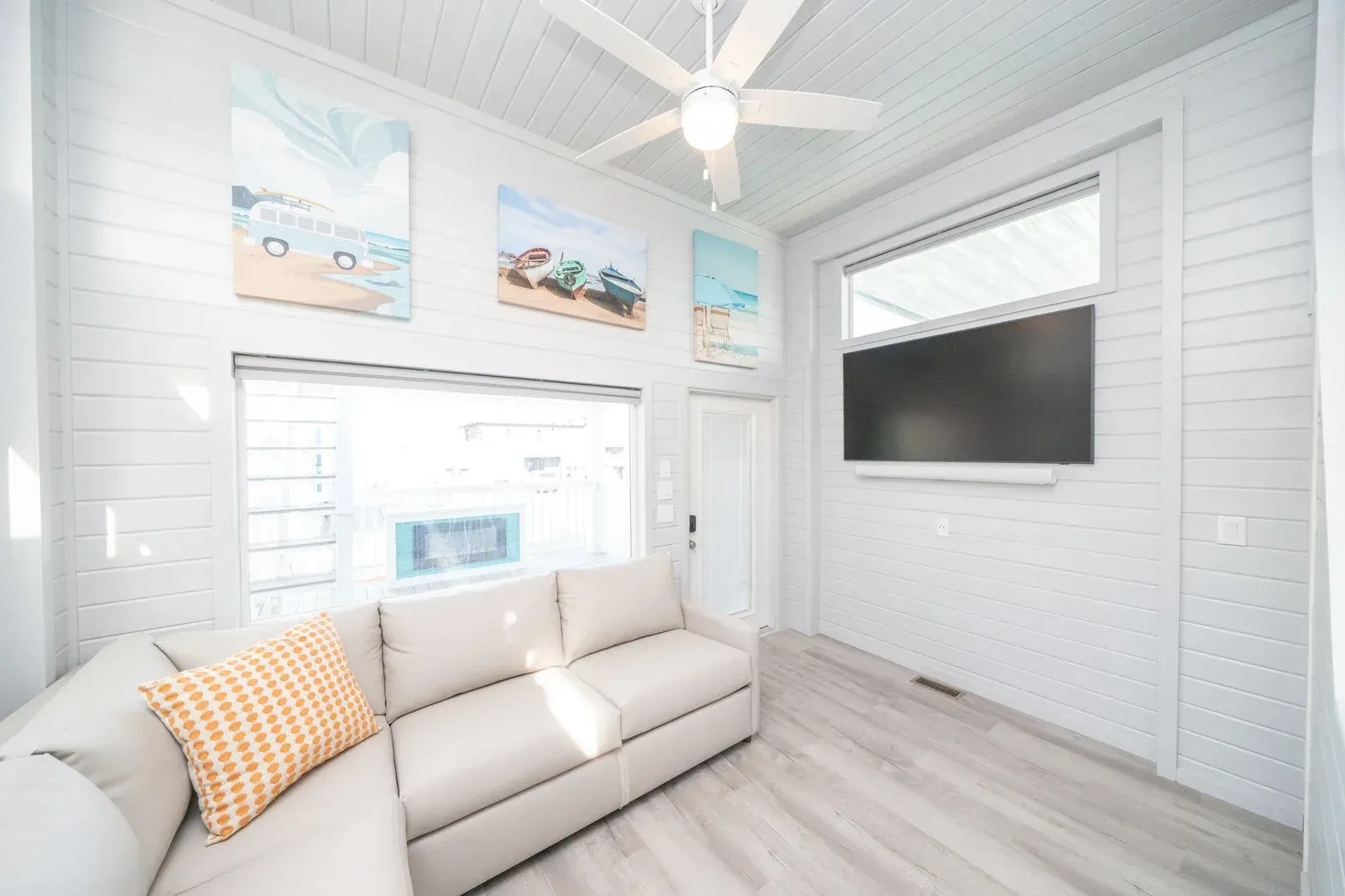 A living room with a couch , television and ceiling fan.
