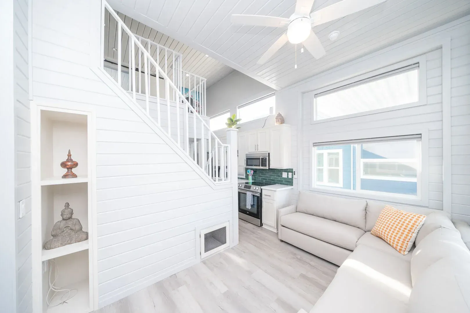 A living room with a couch , stairs and a ceiling fan.