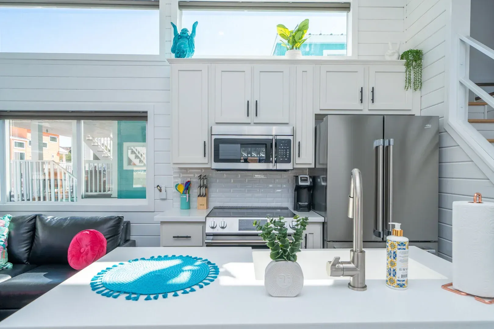 A kitchen with white cabinets , stainless steel appliances , a sink , refrigerator and microwave.