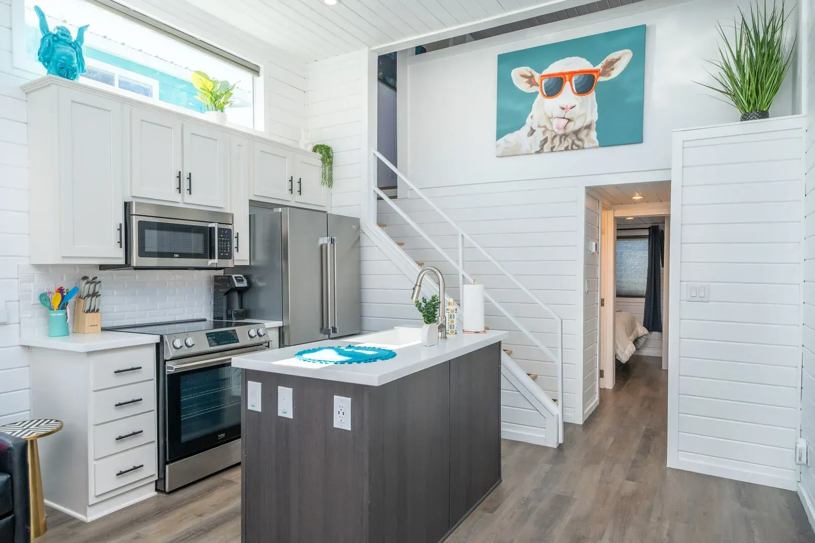 A kitchen with a painting of a sheep on the wall.