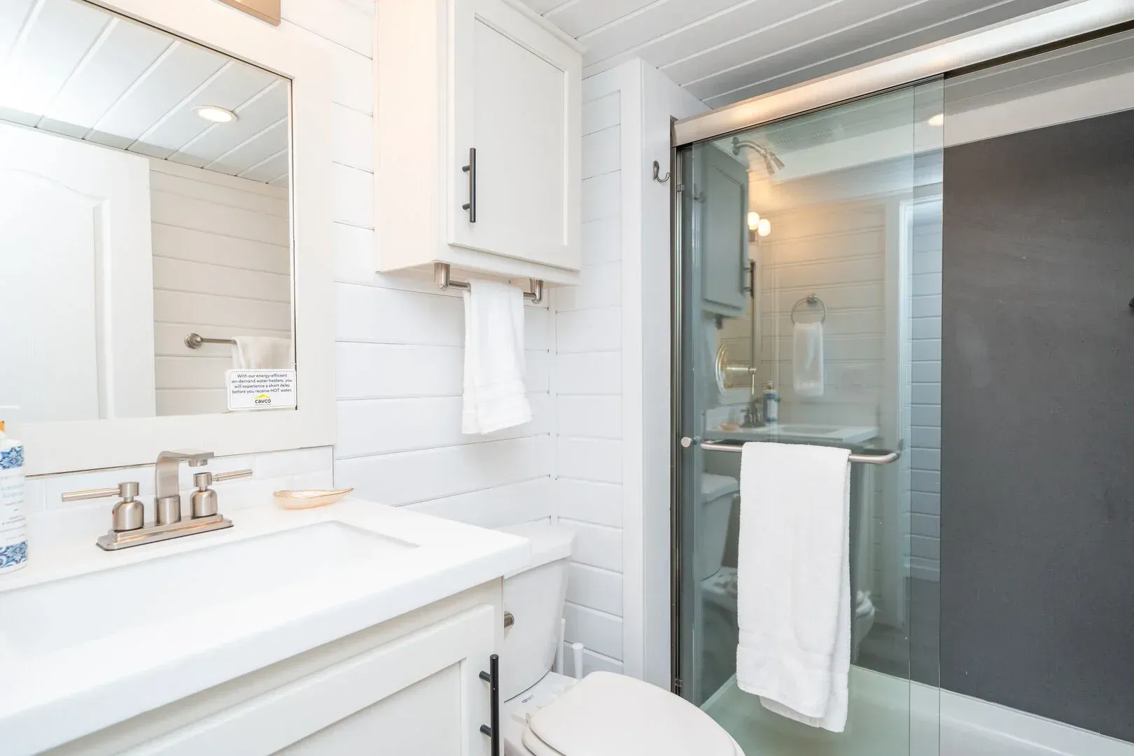 A bathroom with a toilet , sink , mirror and shower.