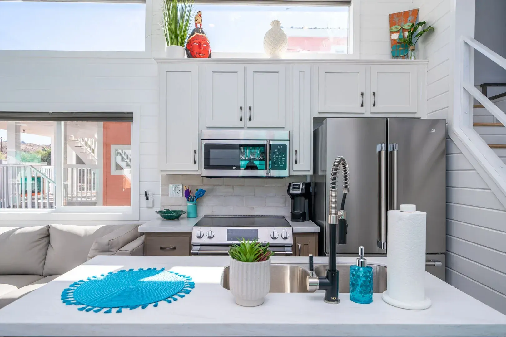 A kitchen with white cabinets , stainless steel appliances , a sink , microwave and refrigerator.