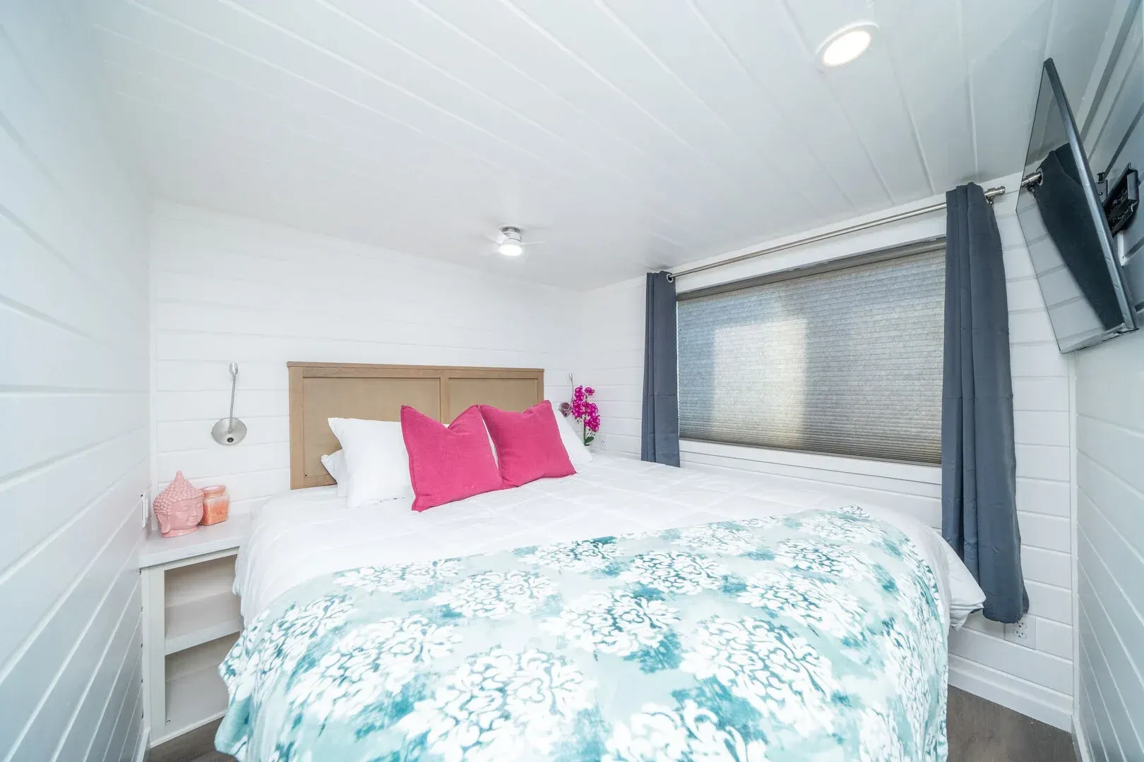 A bedroom with a bed , television , and window.