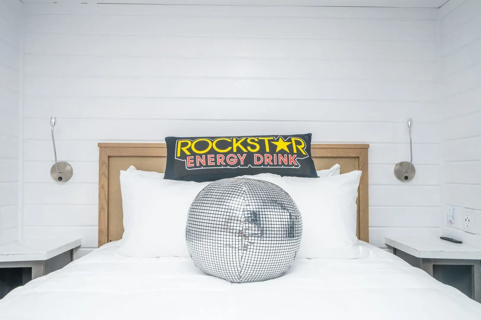 A bed with a disco ball pillow and a rockstar energy drink sign on it.
