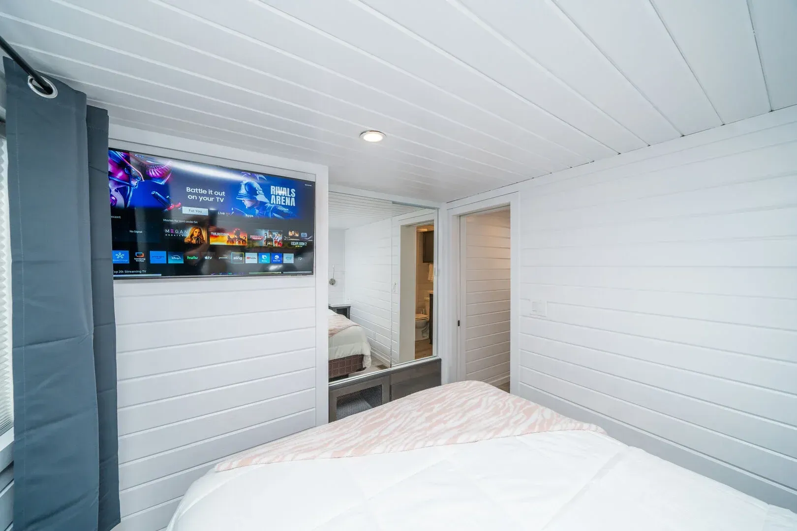 A bedroom with a bed , television and mirror.