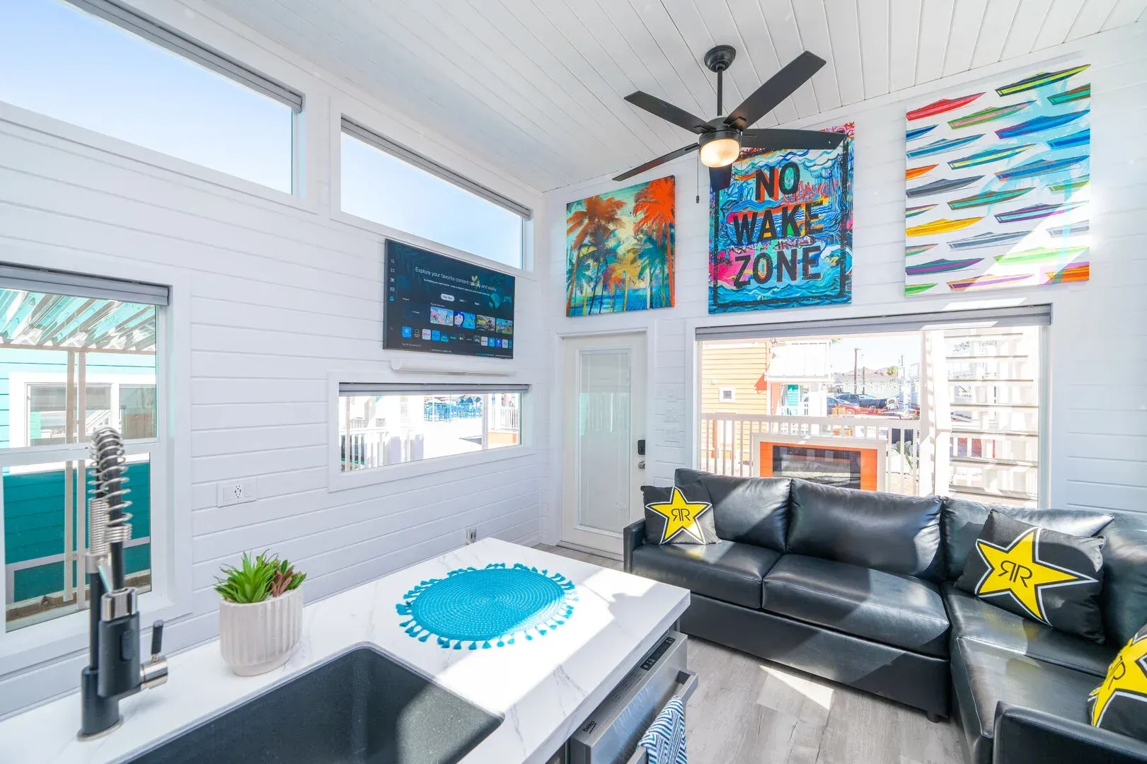 A living room with a couch , sink , and ceiling fan.