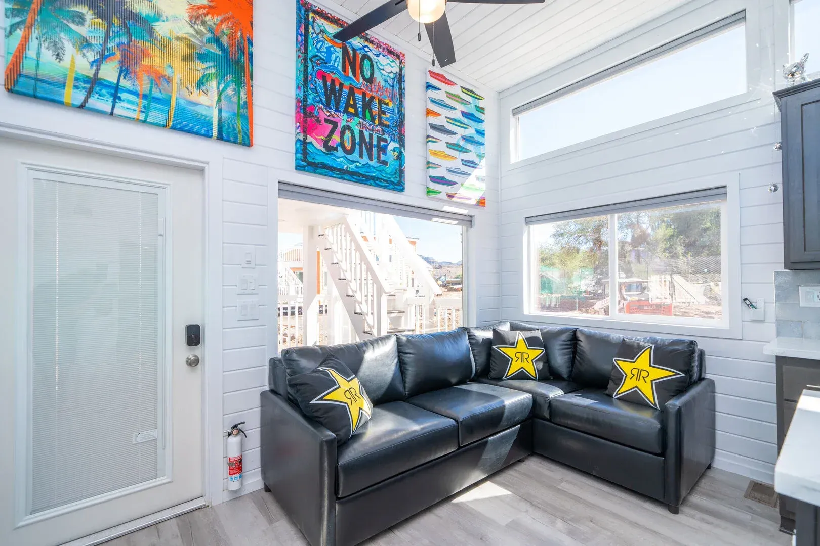 A living room with a black sectional couch and a ceiling fan.