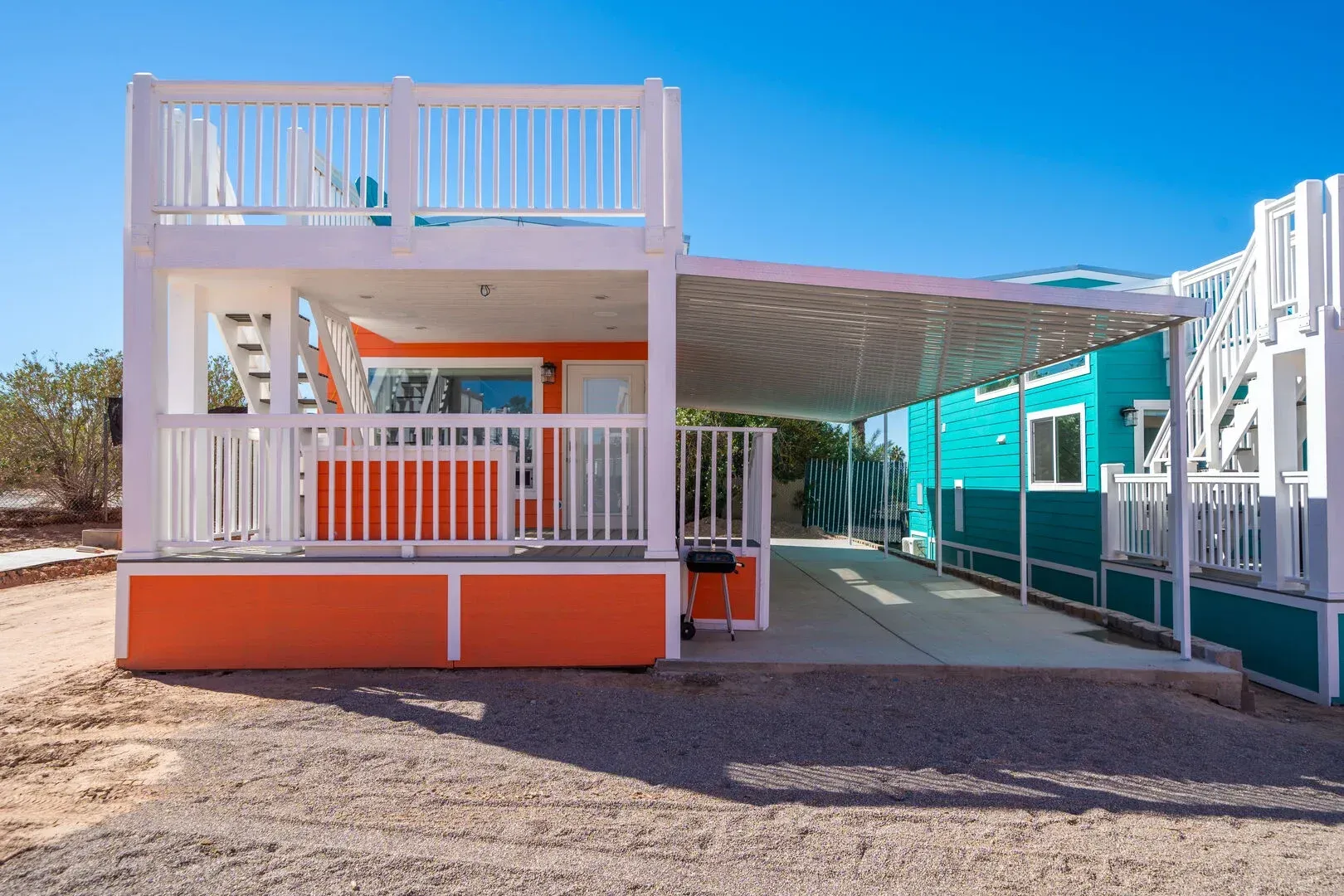 A mobile home with a balcony and a carport in front of it.