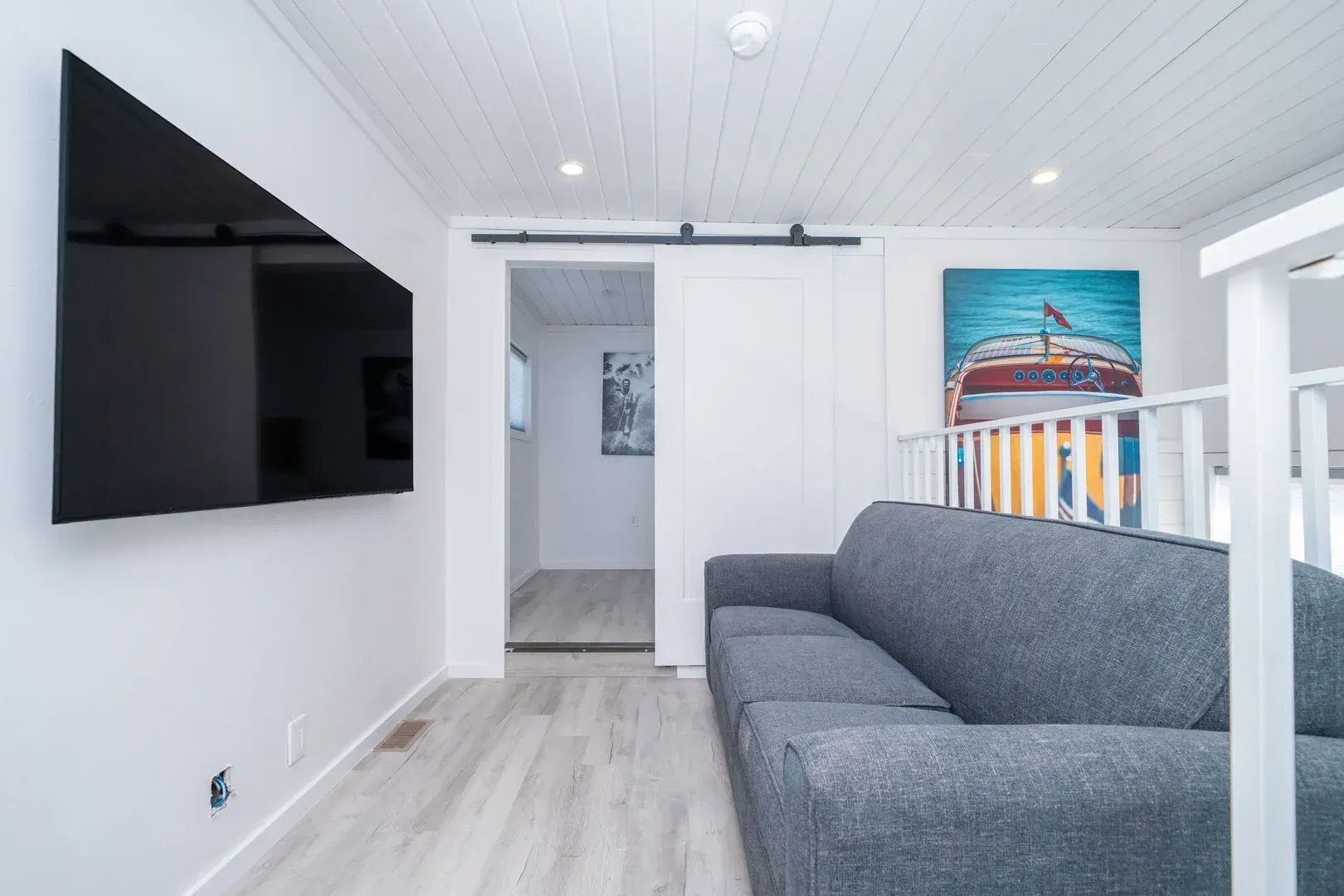 A living room with a couch and a flat screen tv on the wall.
