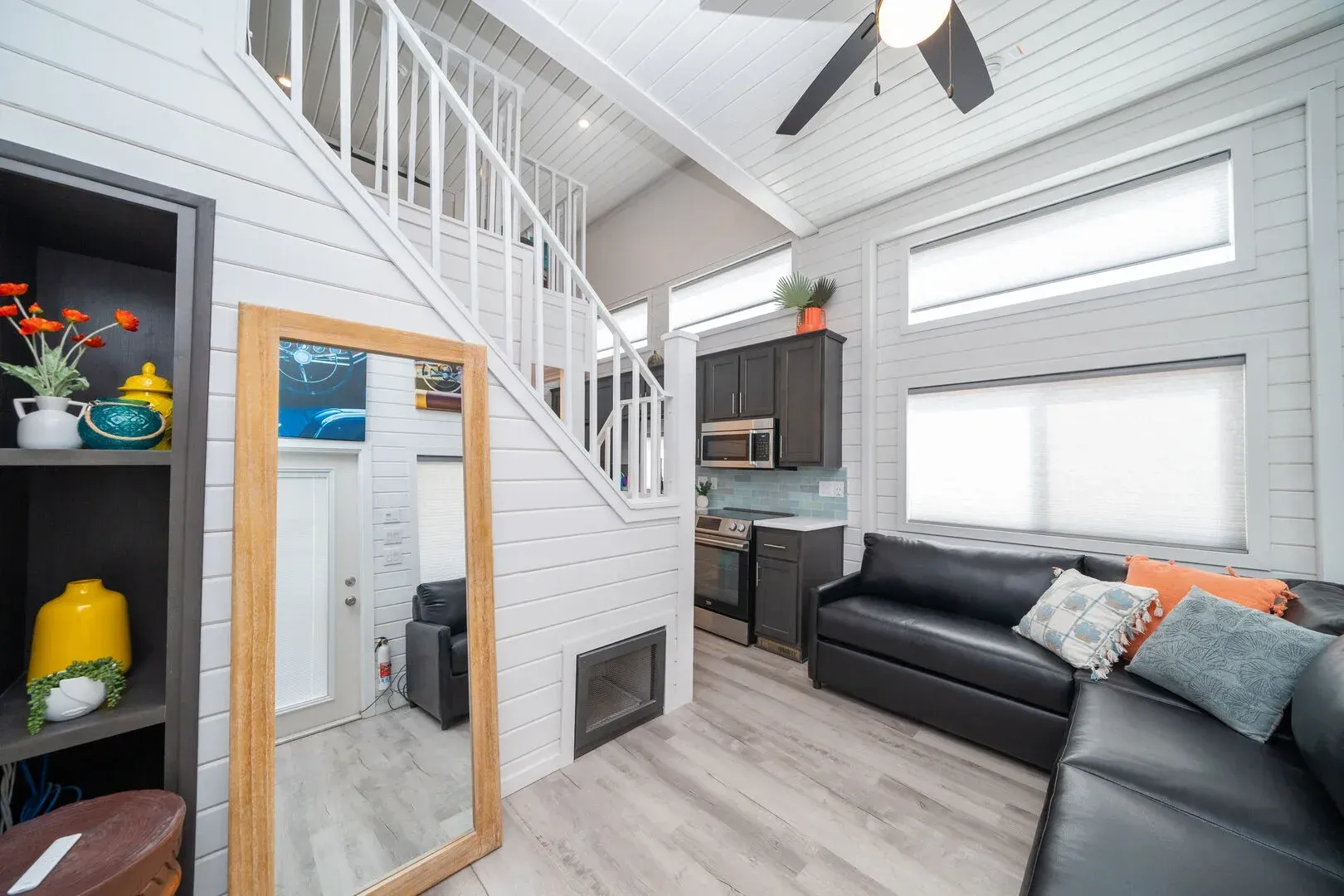 A living room with a couch , mirror and stairs.