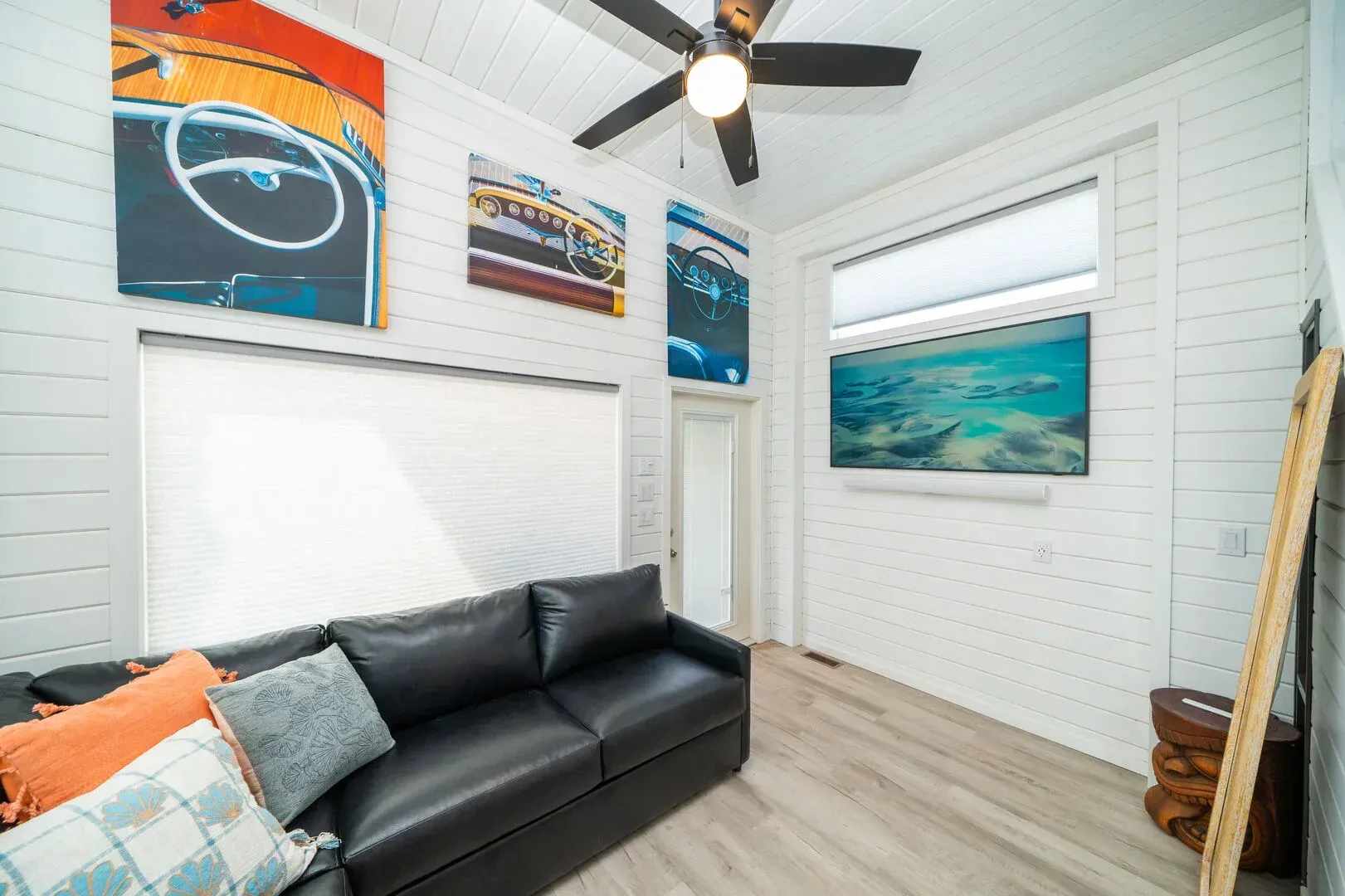 A living room with a black couch and a ceiling fan.
