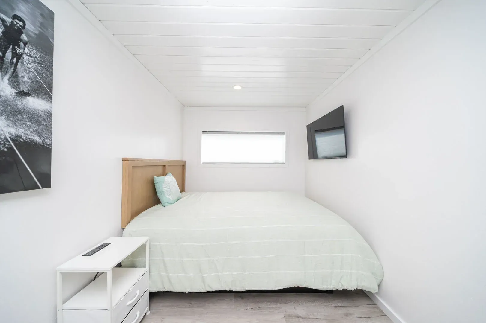 A bedroom with a bed and a television on the wall.
