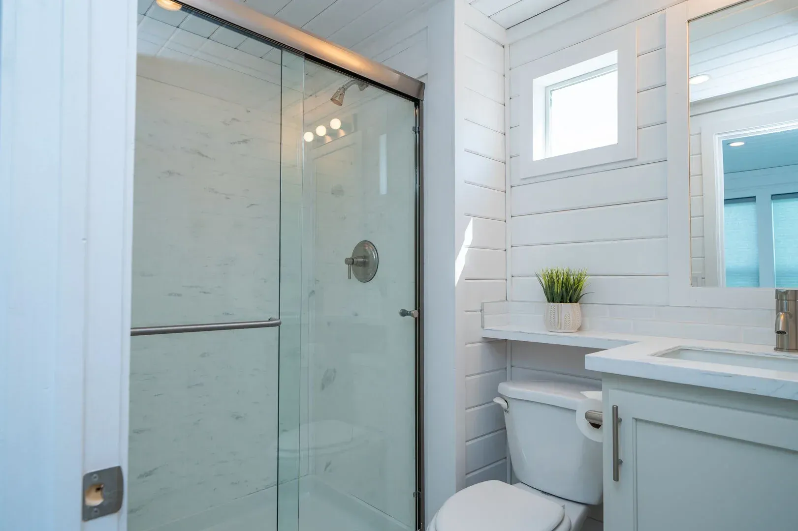 A bathroom with a toilet , sink and shower with a glass door.