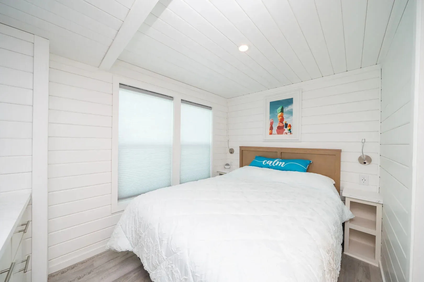 A bedroom with a king size bed and two windows.