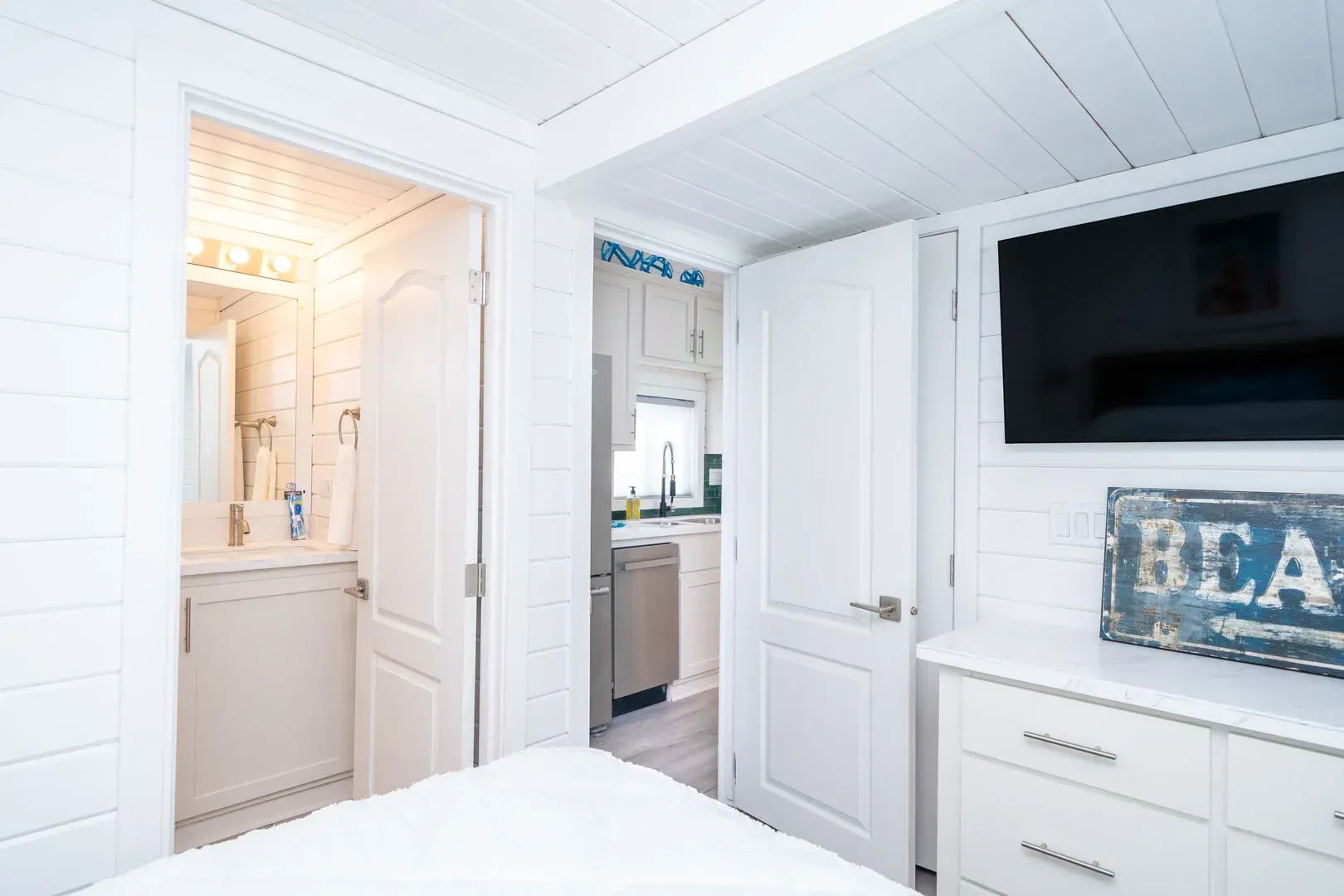 A bedroom with a bed , dresser , television and bathroom.