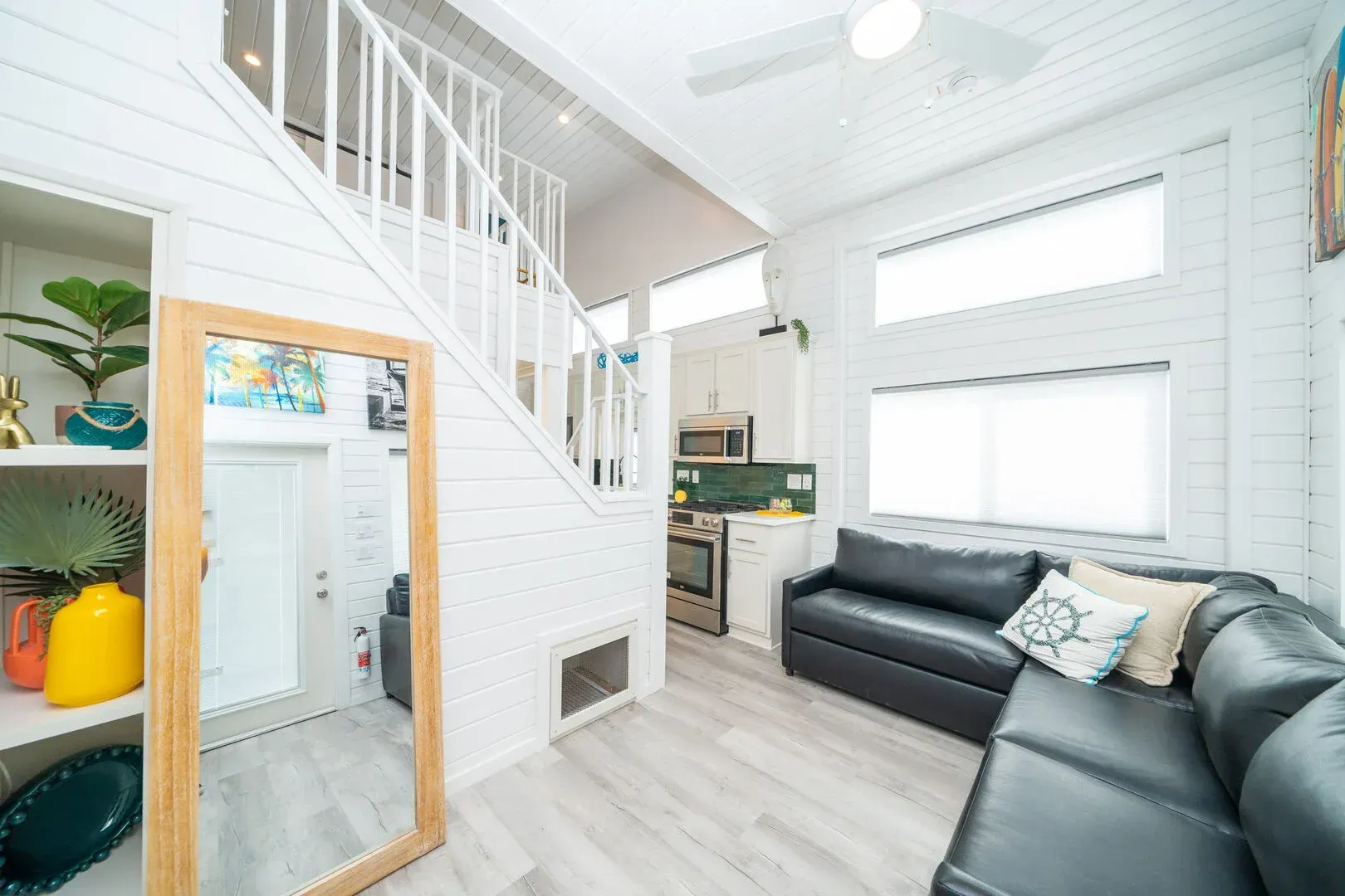 A living room with a couch , mirror and stairs.