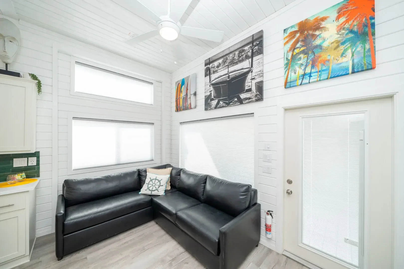 A living room with a black couch and a ceiling fan.