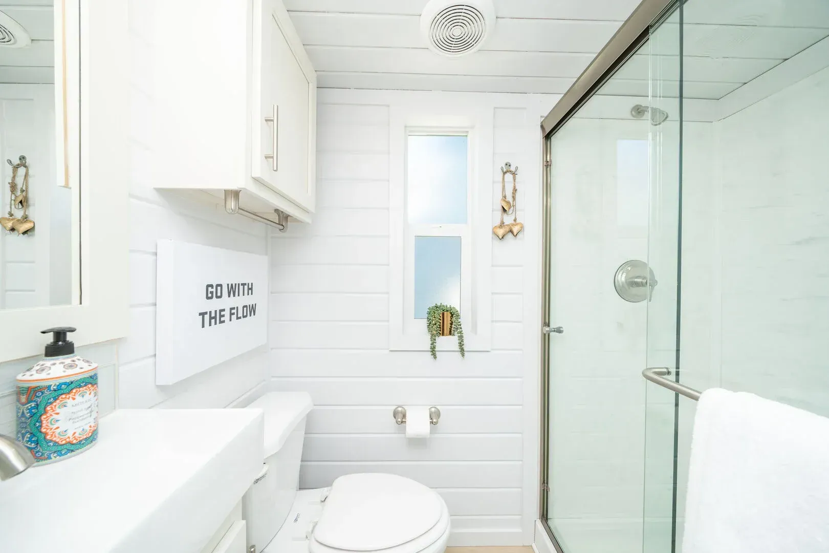 A bathroom with a toilet , sink , mirror and shower.