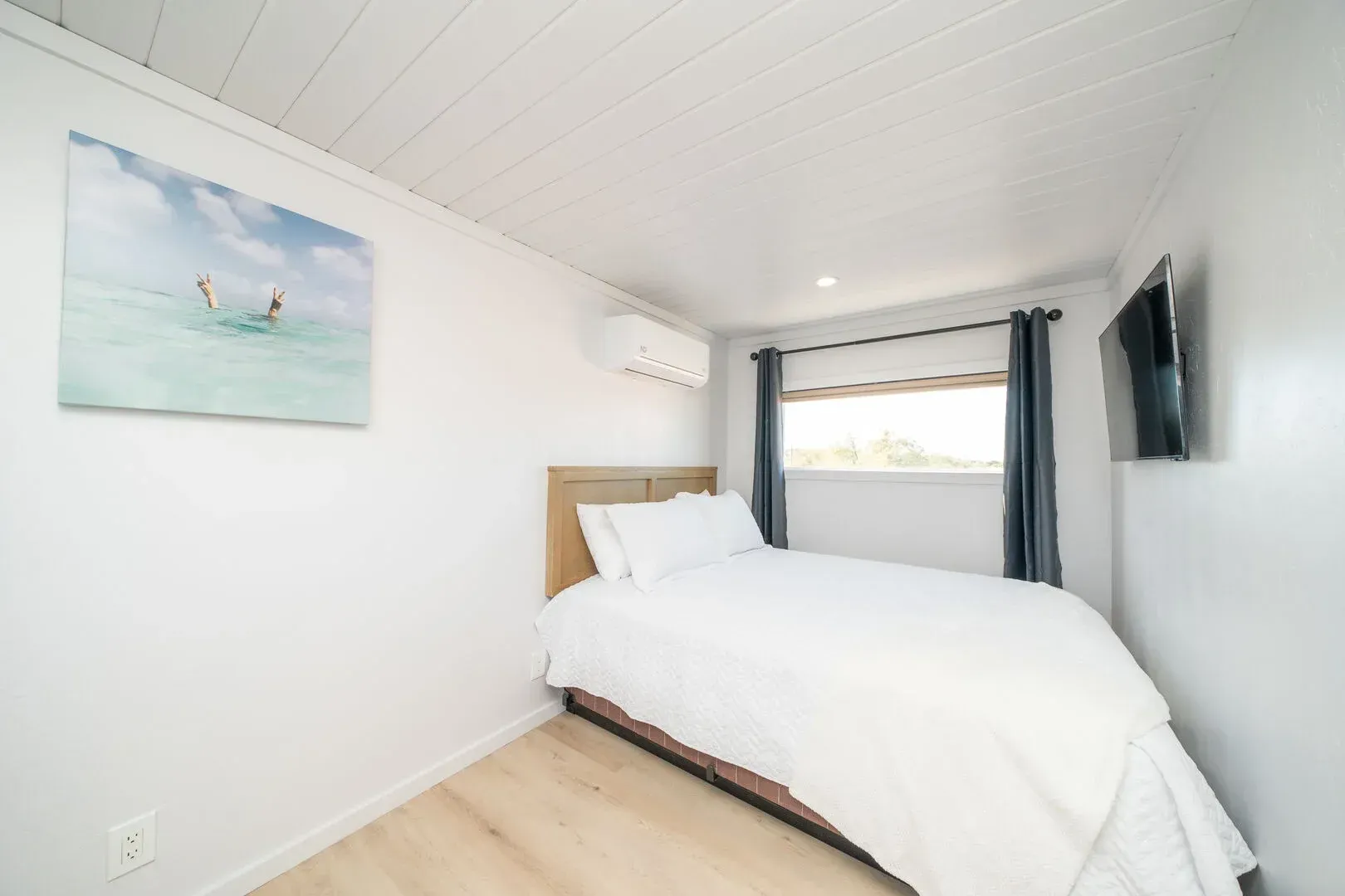 A bedroom with a bed and a television on the wall.