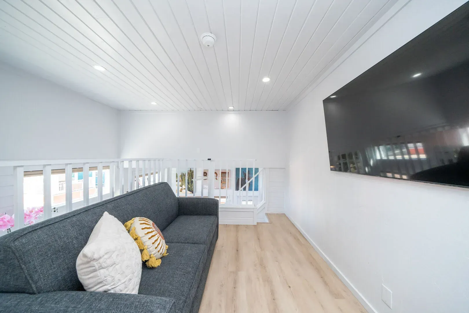 A living room with a couch and a television on the wall.